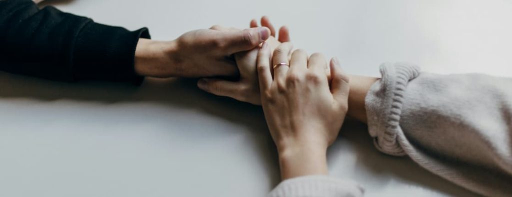 白いテーブルの上で、手を重ね合わせる男女。