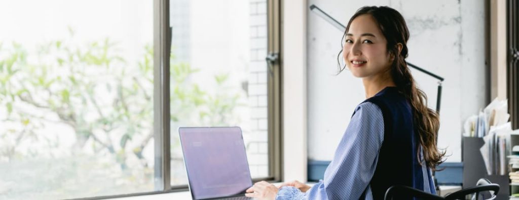 前向きで明るい表情を見せる女性エンジニアの写真。リラックスできる環境で作業をしている様子。