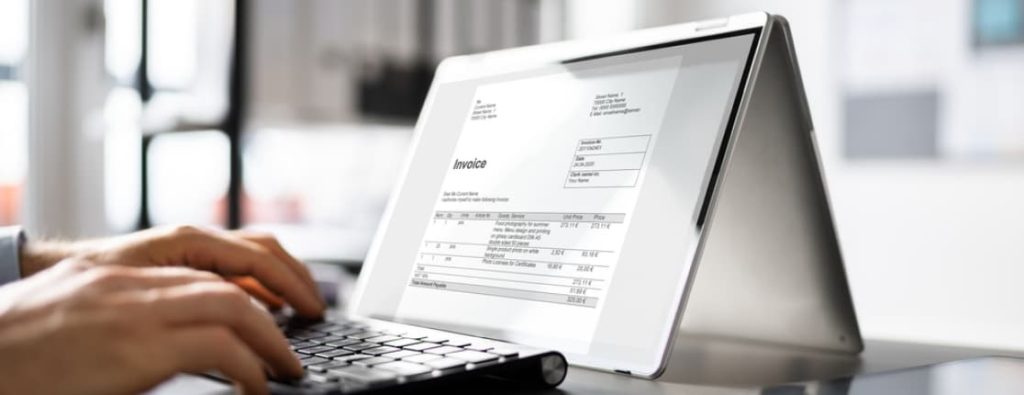 キーボードを操作する手元と、画面に表示された「Invoice」の文字。