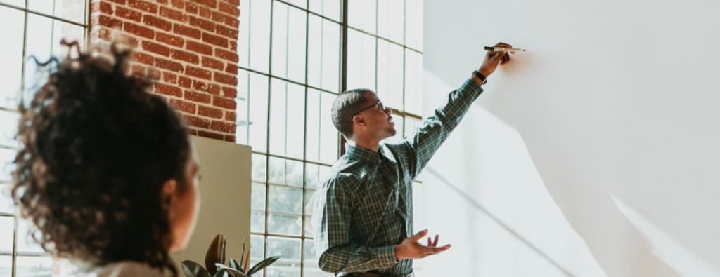 エージェントのコンサルタントと共に、ホワイトボードを使って将来的なキャリアパスや目標とする単価までのロードマップを可視化するフリーランスエンジニア。