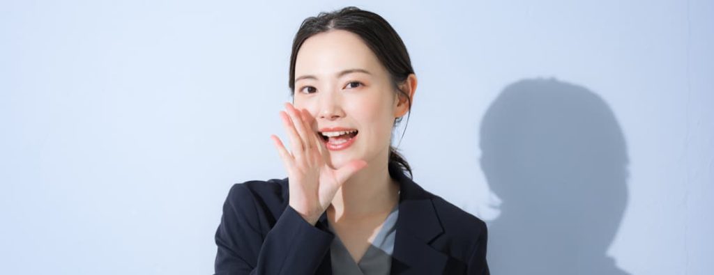 口元に手を当てて、笑顔でメリットを呼びかけている若い女性の写真。