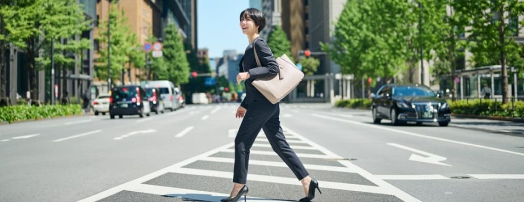 フリーランスエンジニアとして独立し、晴れやかな表情でビジネス街を歩き出す女性。