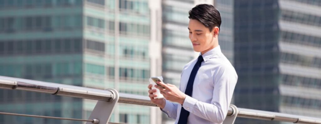 高層ビルを背景に、スマートフォンで開業届の電子申請を行う男性の写真。