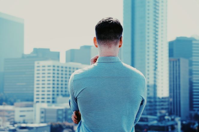 都会のビル群を見ながら将来を考える男性