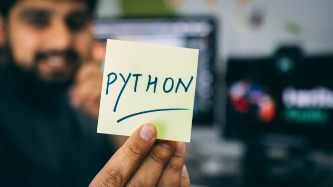 「Python」と書かれたメモを見せる男性