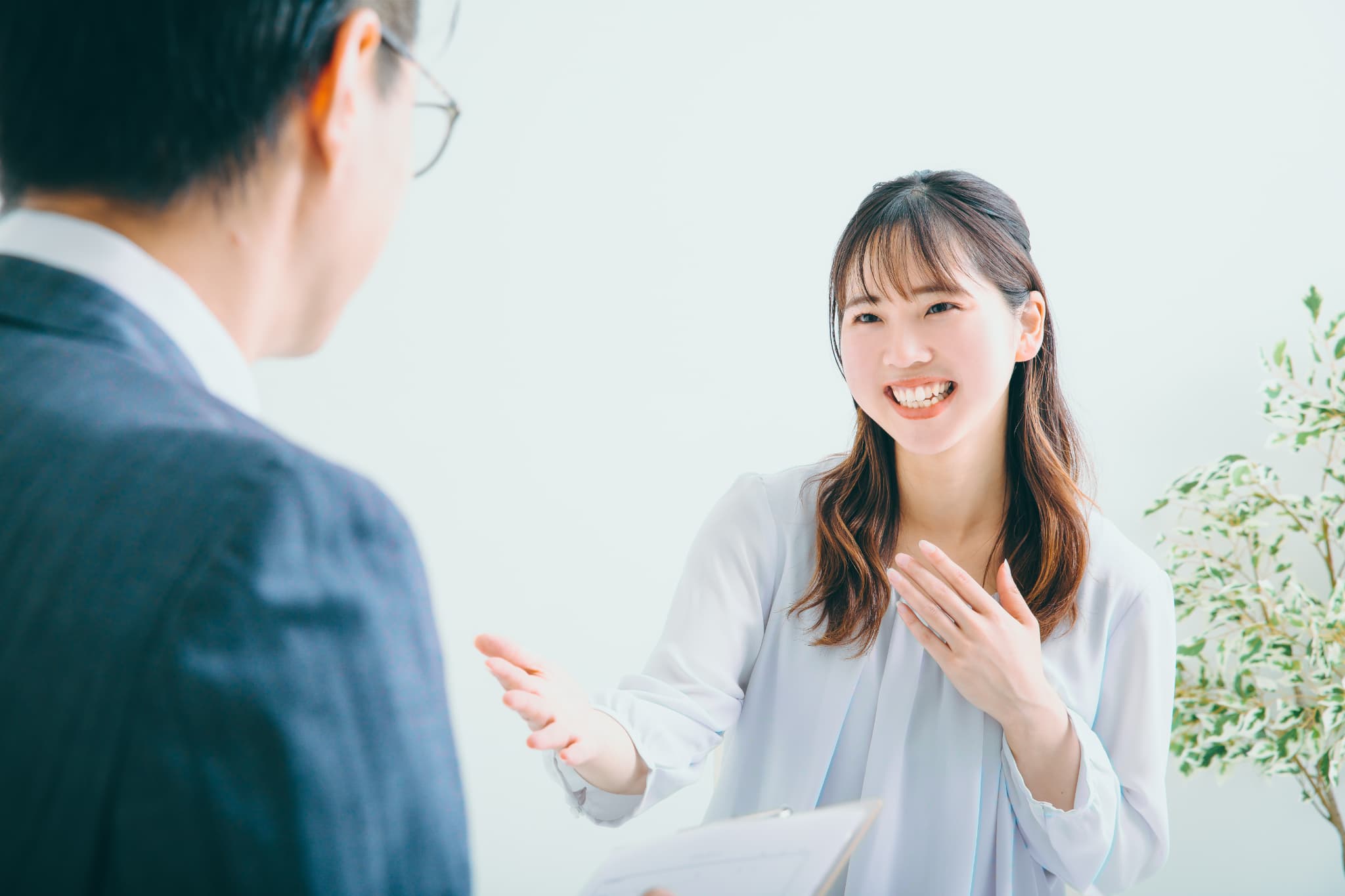 男性面接官と対話する、笑顔の女性応募者の様子。女性は身ぶり手ぶりを交えながら熱心に話している。